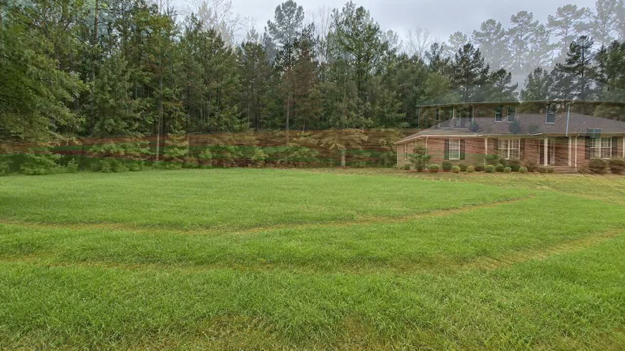 A rural back yard going from bare red clay after a septic installation to established green lawn